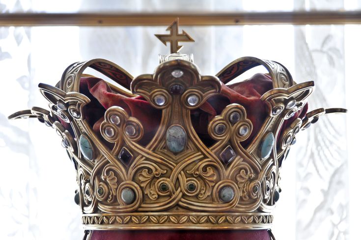 a gold crown sitting on top of a red table next to a window sill