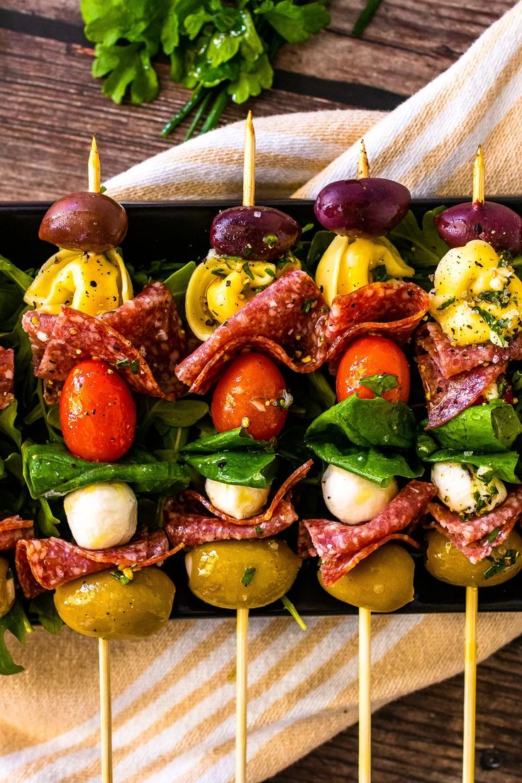 several skewers filled with different types of food on top of a wooden table