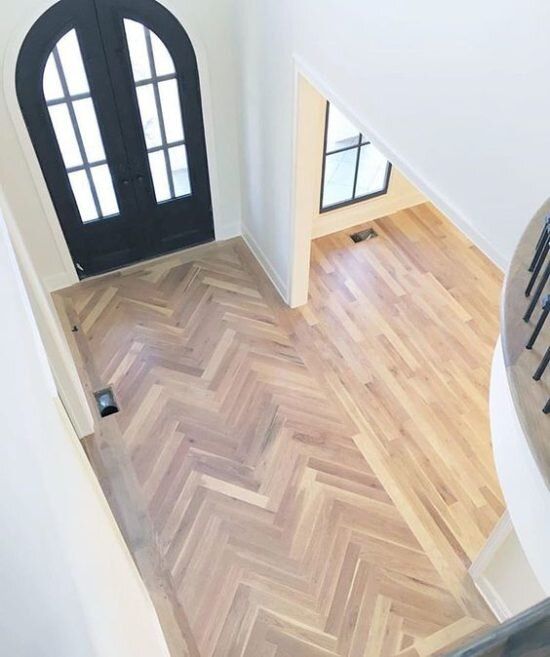 an aerial view of a foyer with wooden floors and black doors, looking down at the entryway