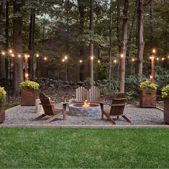 an outdoor fire pit surrounded by wooden chairs and potted plants with lights on them