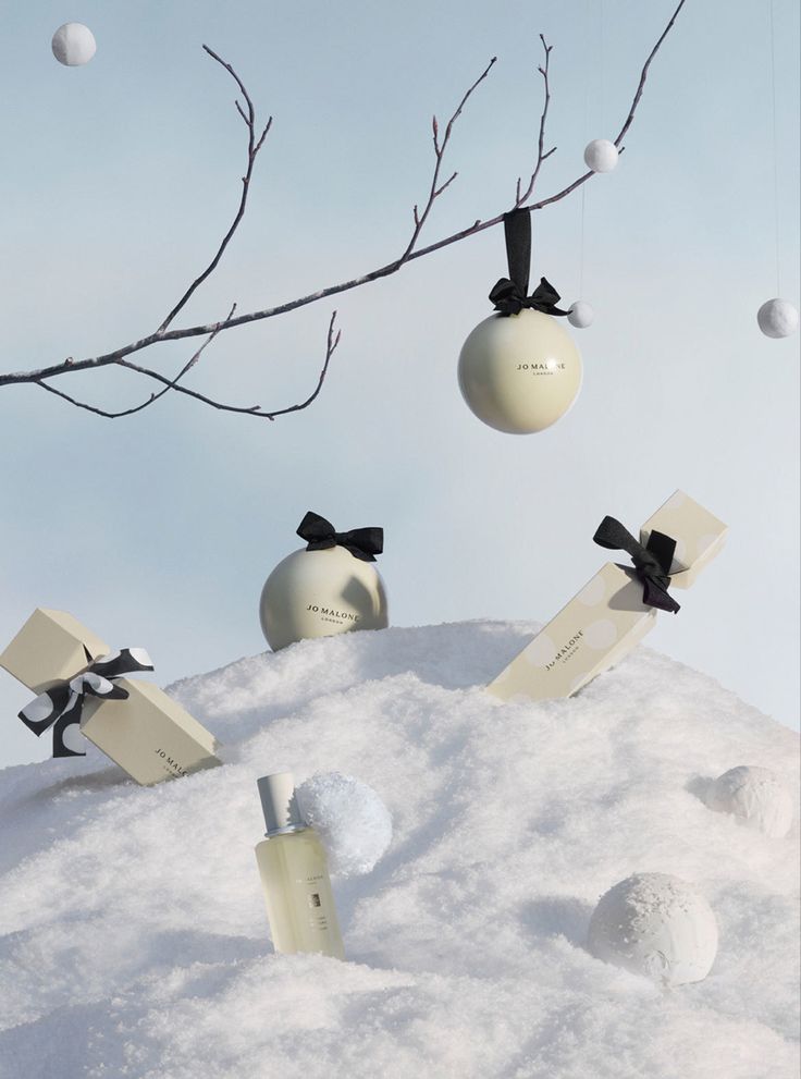 an image of christmas decorations in the snow with balls and gifts hanging from tree branches