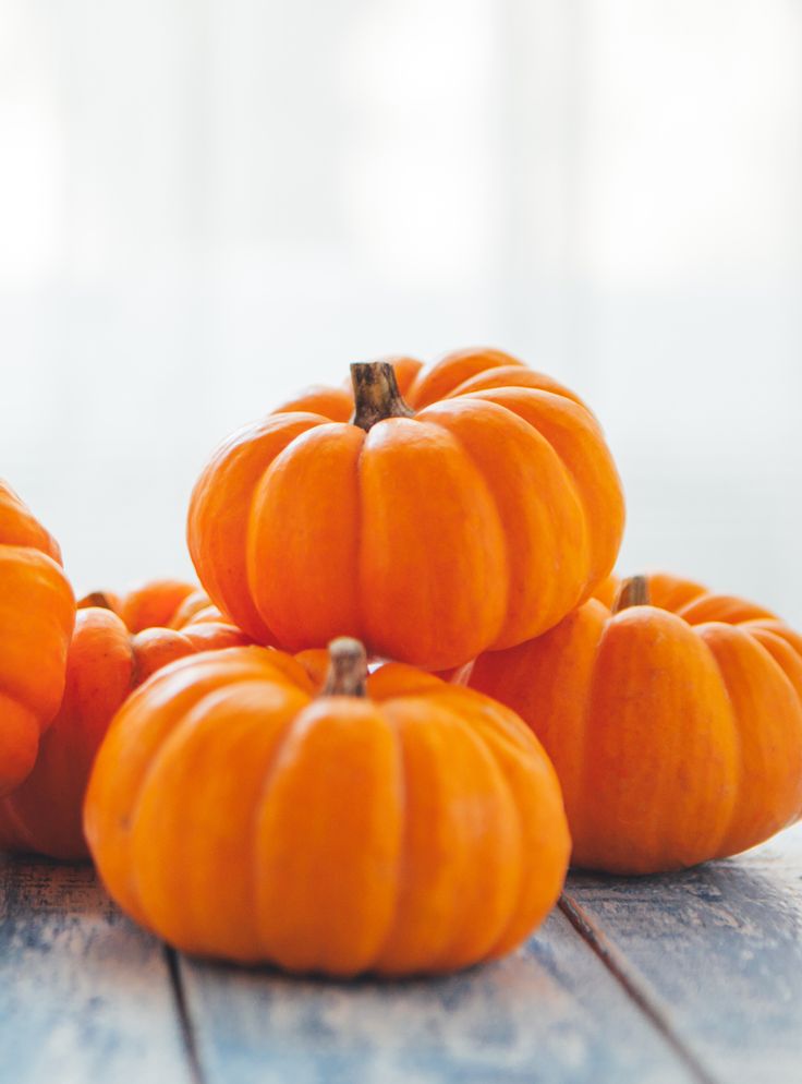 several small pumpkins sitting on top of a wooden table