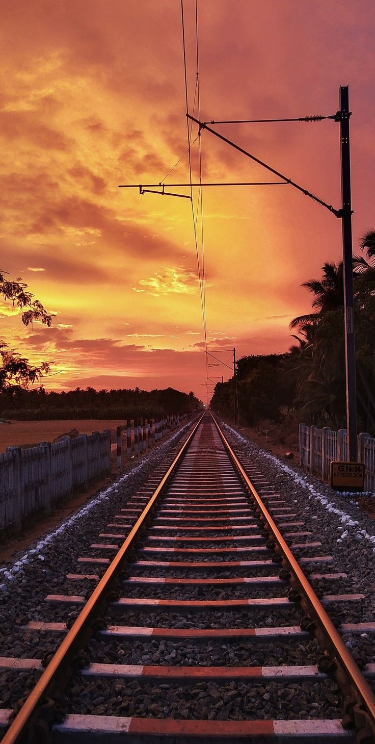 a train track with the sun setting in the background