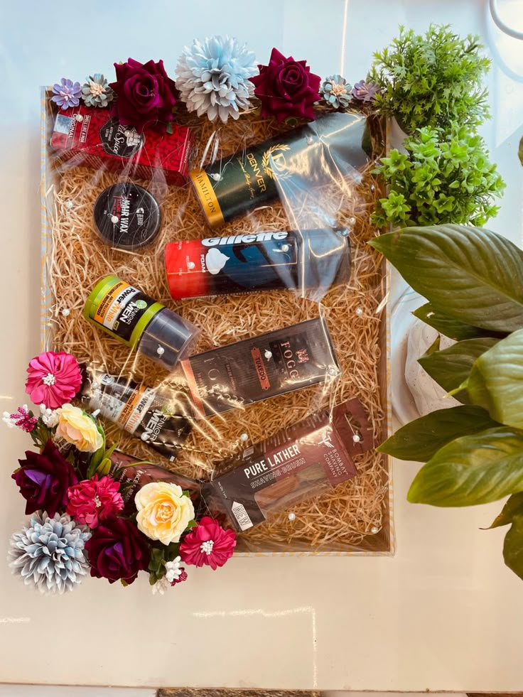 an arrangement of personal care products and flowers in a gift box on top of a table