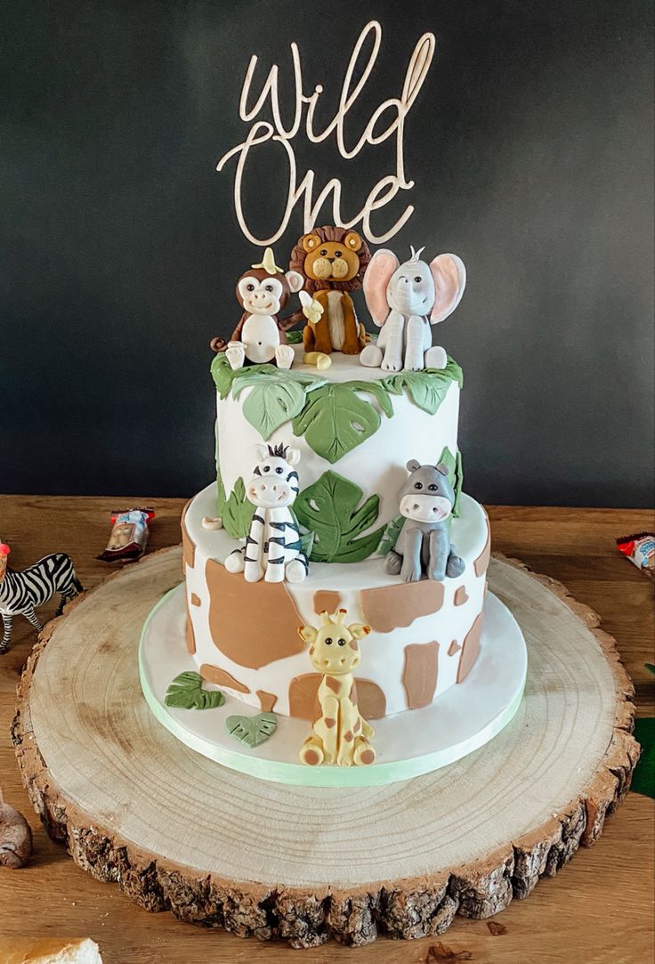 a three tiered cake decorated with animals and the words wild one on it's top