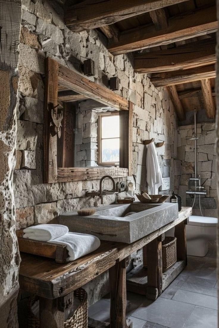 a rustic bathroom with stone walls and flooring, two sinks are on the counter