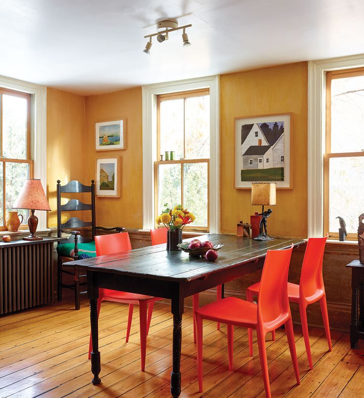 a dining room with orange chairs and wooden floors