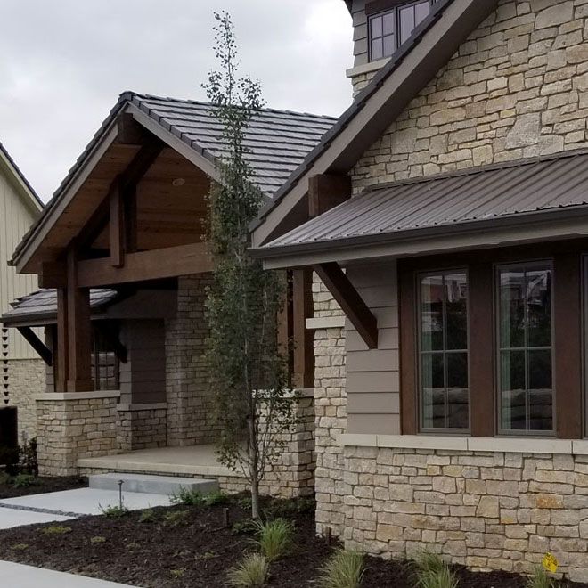 the front of a house with stone and wood sidings on it's sides