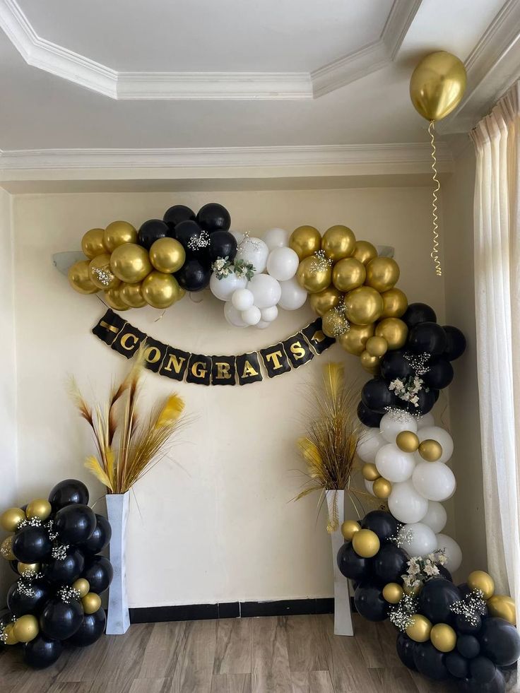 black and gold balloon arch with congratulations banner