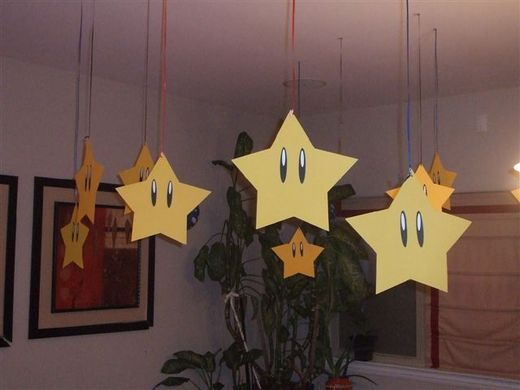 three yellow stars hanging from the ceiling in front of a potted plant with eyes drawn on them