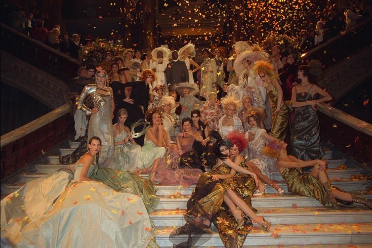 a group of people dressed in fancy clothing sitting on steps with confetti falling all over them