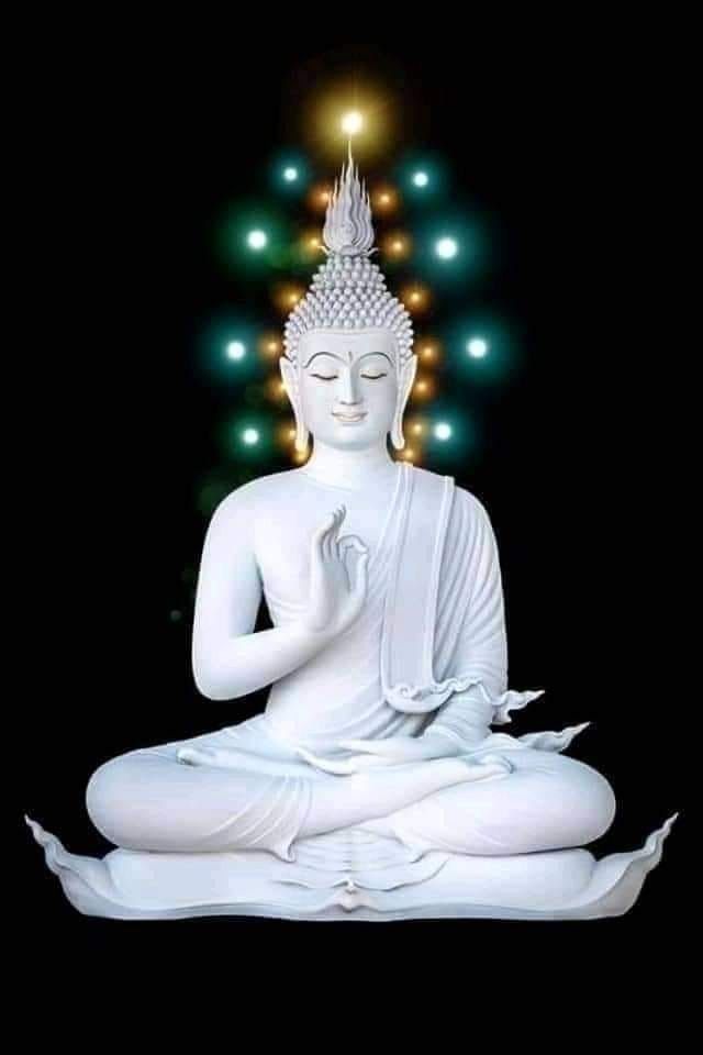 a white buddha statue sitting on top of a black surface with lights in the background