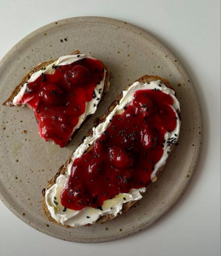 two pieces of bread with cream cheese and jelly on them