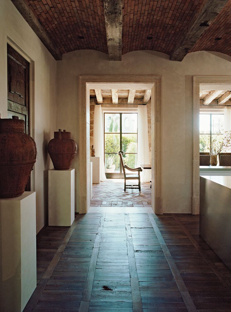 an empty room with two vases and a chair in the center, on either side of a doorway