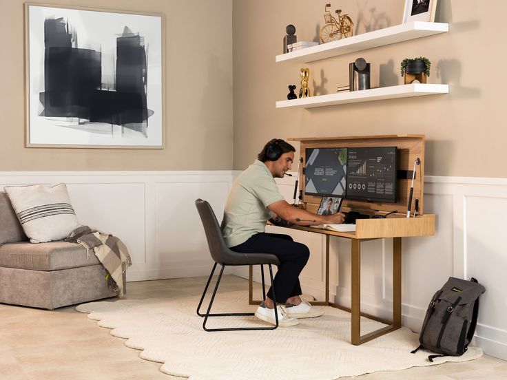 a person sitting at a desk with a computer on it and a bag next to him