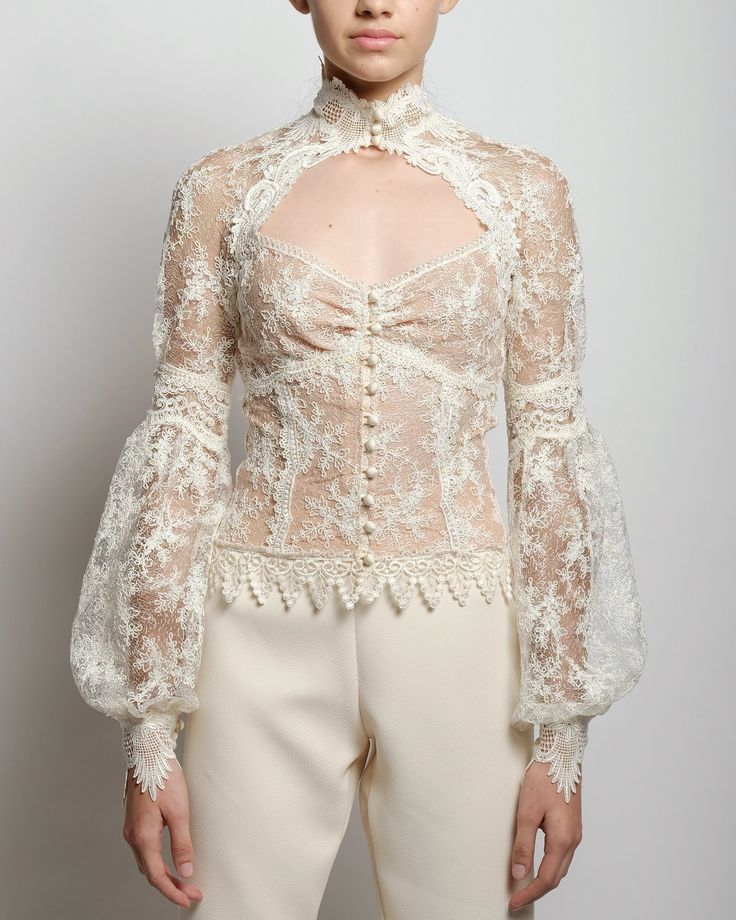 A sheer lace blouse with a high neck and hand placed embroidery at collar and cuff closures. The Eliza blouse features a fitted empire cut along with front décolletage and raglan romantic billow sleeves. French lace lined with nude color mesh Delicate satin button closure for collar, cuffs and front Dry clean only Each piece is made to order and handcrafted in our atelier. Slight variations may occur as each piece is unique. Alternative Wedding Dresses, Romantic Blouses, High Neck Blouse, Unique Blouse, French Lace, Dress Cuts, Dream Clothes, Sheer Blouse, Lace Blouse