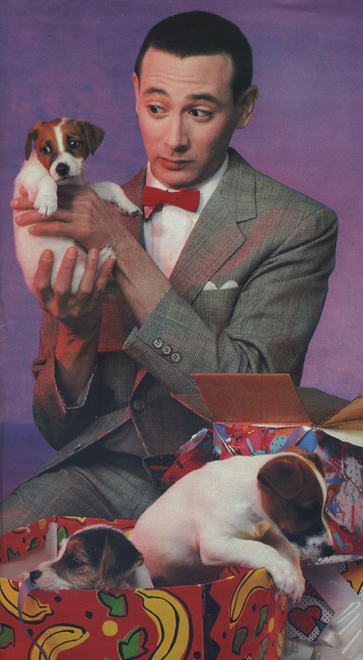 a man in a suit and bow tie holding a small dog on top of a box