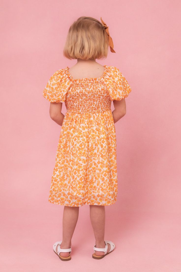 Get ready to turn heads in the Mini Serendipity Dress! This fun and playful dress features a vibrant yellow and white floral print on flowy chiffon fabric. The square neckline with ruffle detailing adds a touch of femininity, while the half-length puff sleeves with elastic band provide a comfortable and flattering fit. With a knee-length skirt and convenient pockets, this dress is as functional as it is stylish. The smocked bodice and stretch fabric at the shoulders, neckline, and bodice make fo Playful Smocked Floral Dress For Summer, Playful Smocked Dress With Floral Print For Summer, Playful Floral Smocked Dress For Summer, Playful Summer Smocked Dress With Floral Print, Playful Dress With Smocked Back For Vacation, Playful Dresses With Smocked Bodice For Spring, Playful Vacation Dress With Smocked Back, Playful Spring Dresses With Smocked Bodice, Yellow Smocked Bodice Flowy Dress