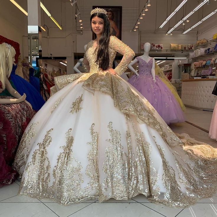 a woman is standing in front of some mannequins wearing dresses with gold sequins on them