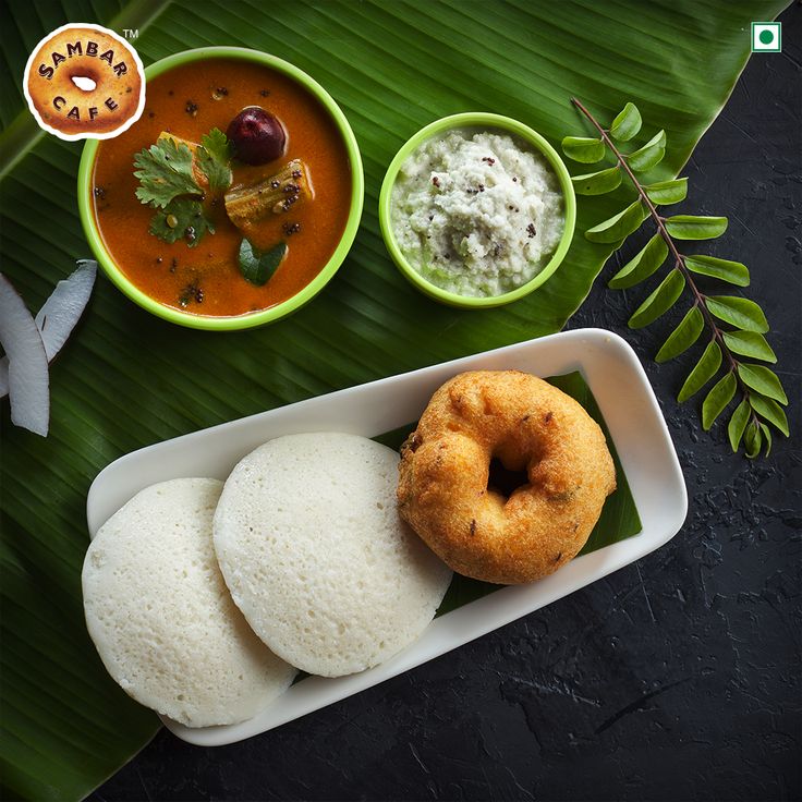 three different types of food in bowls on a tray next to a banana leaf and spoons