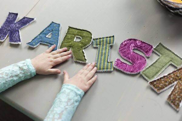 two children are playing with letters made out of fabric and thread on a table top