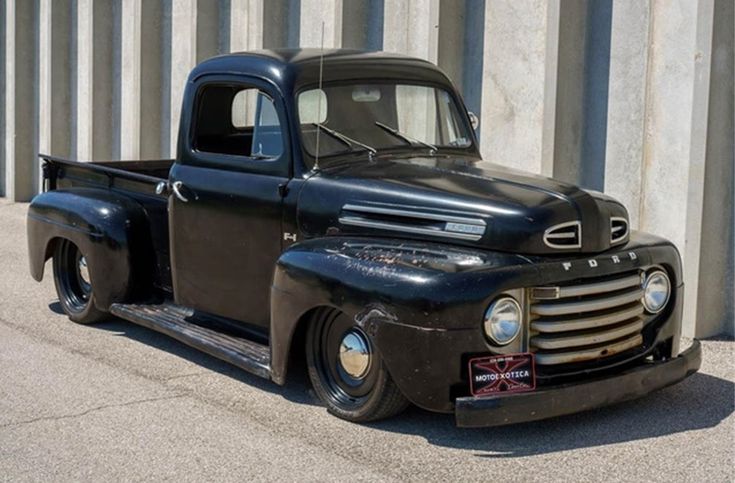 an old black truck parked in front of a building