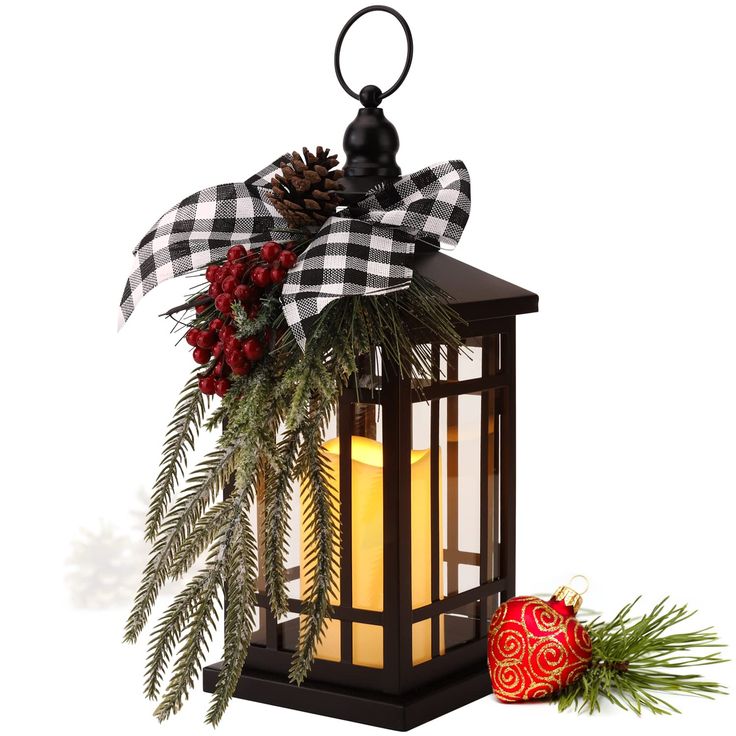 a lantern with a christmas decoration on it and a pine cone hanging from the top