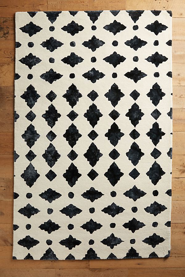 a black and white area rug sitting on top of a wooden floor