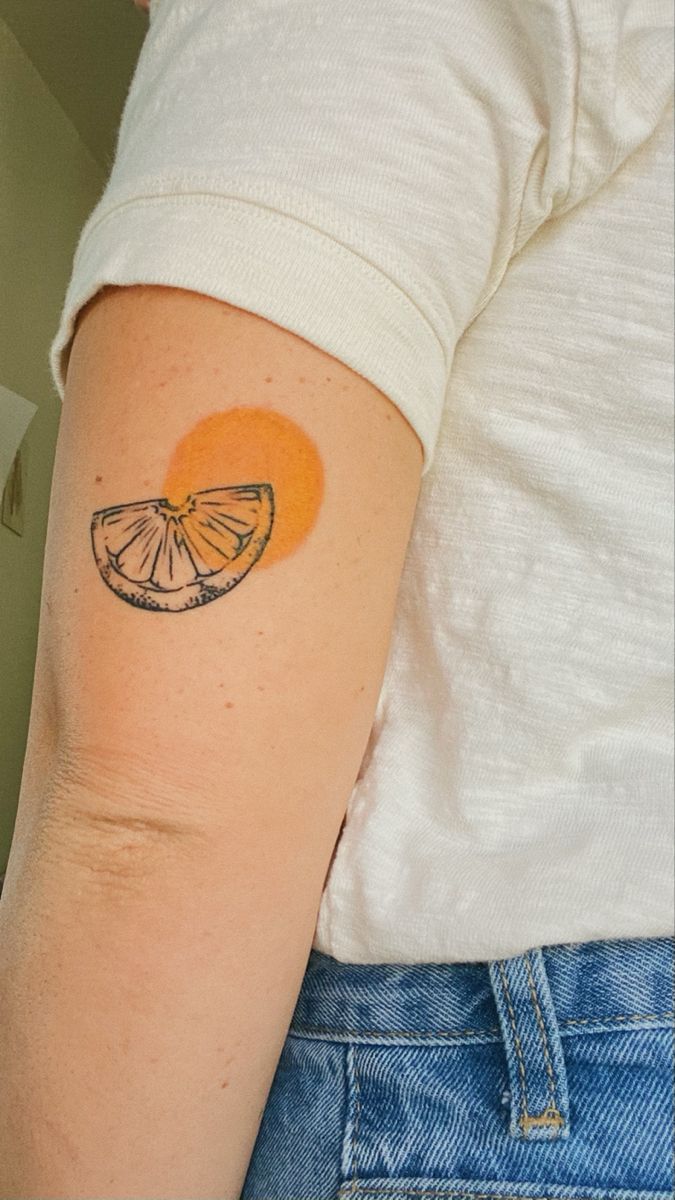 a person with a tattoo on their arm and an orange slice in the shape of a heart