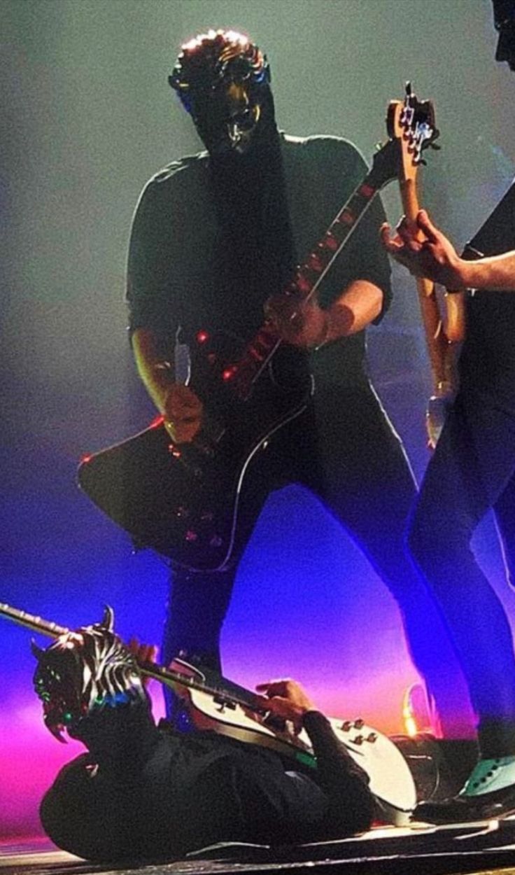 two men in black costumes playing guitars on stage