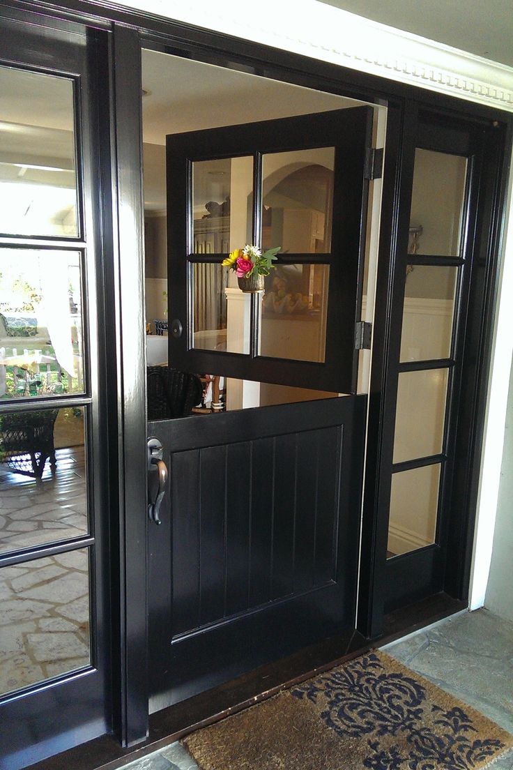 a black door with glass panels and flowers on the top shelf in front of it