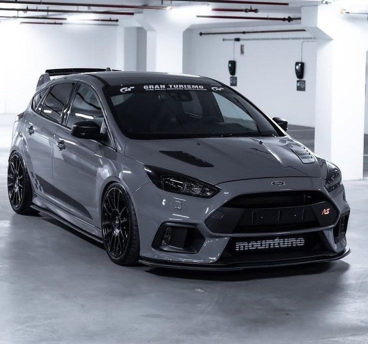 the front end of a grey ford focus st with black rims in a parking garage