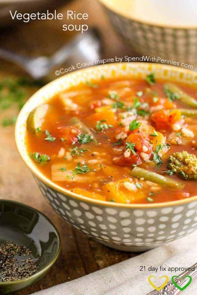 a bowl of vegetable rice soup on a wooden table