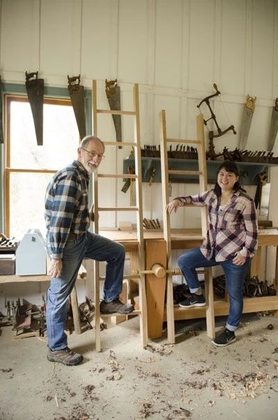 two people standing next to each other in a room with ladders on the wall