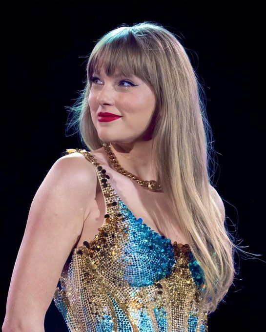 taylor swift wearing a blue dress with gold sequins and red lipstick on stage