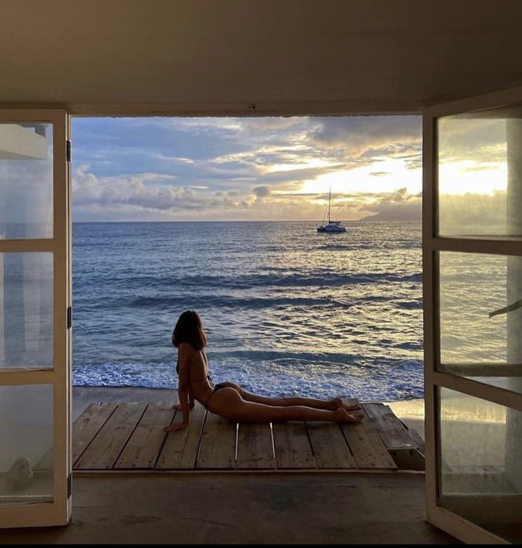 a woman is sitting on a deck looking out at the ocean