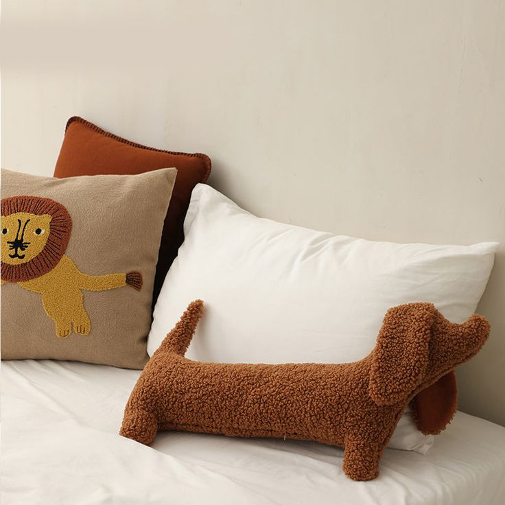 a dog pillow sitting on top of a bed next to a brown stuffed animal toy