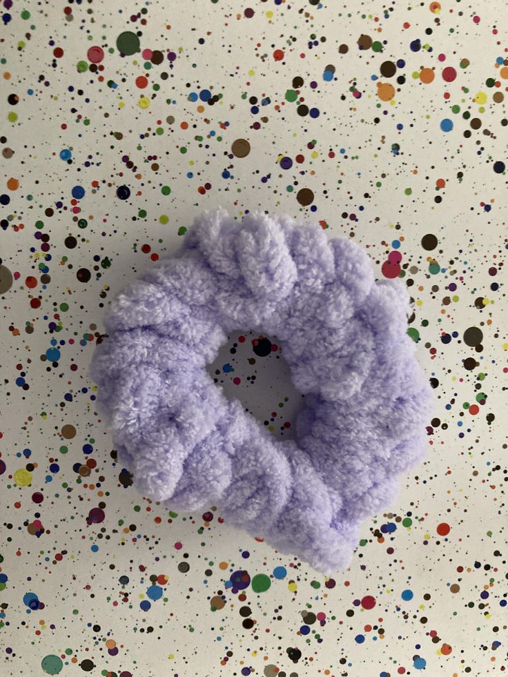 a purple hair scrunch sitting on top of a white table covered in confetti