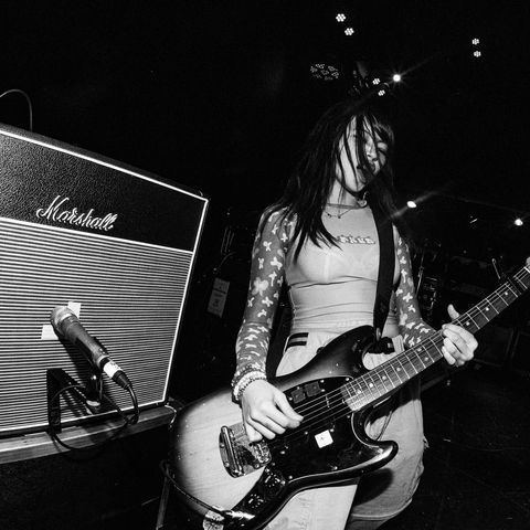 a woman with long hair playing guitar in front of a microphone and amp on stage