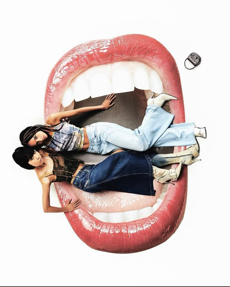 two women laying on top of each other in front of a giant mouth with teeth