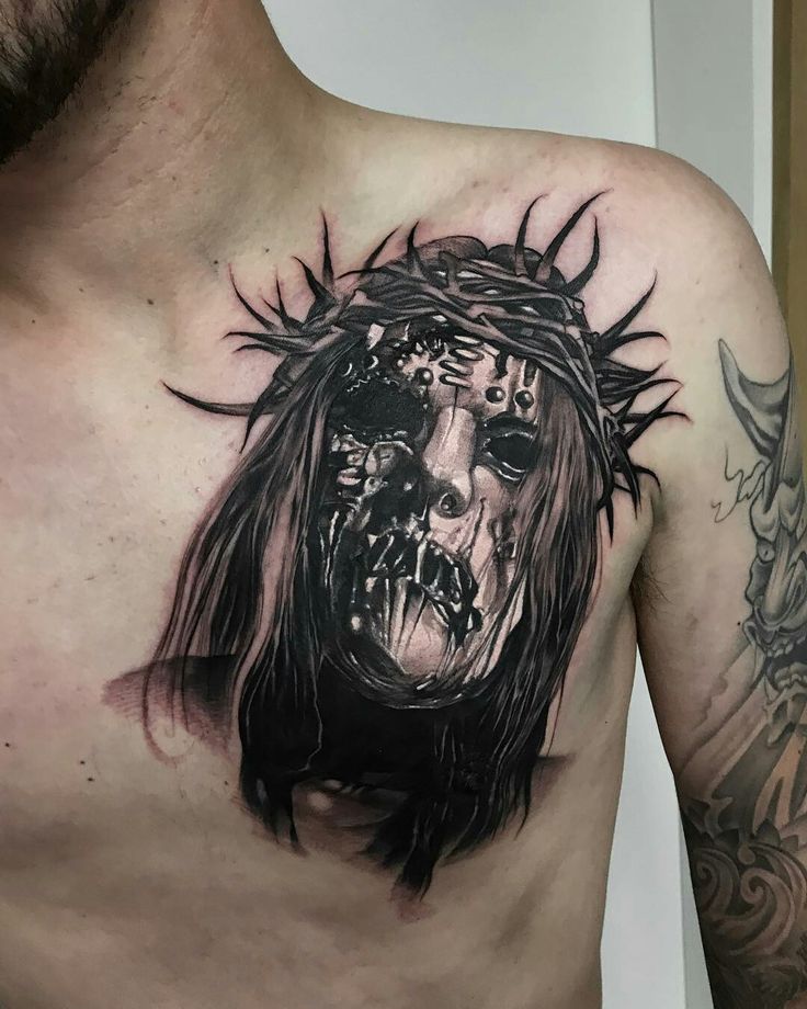 a man's chest with a tattoo of jesus on it and an evil face