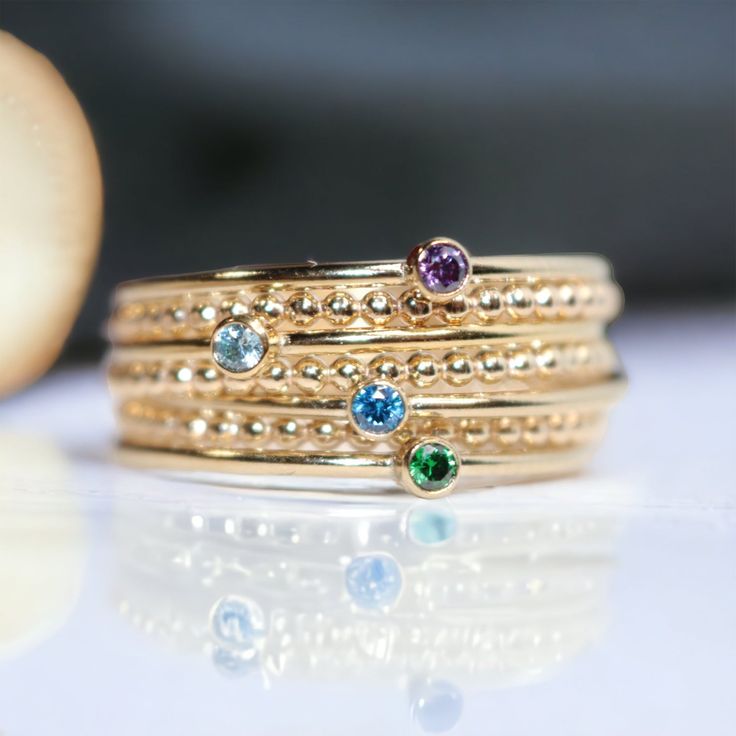 These delicate 14k Gold filled birthstone rings can be worn alone for a minimalist look, or stack multiples to represent your family. These are also the same rings as in our Class Ring Sets, which you can add a second birthstone/school color ring if you wish. Some pictures show optional beaded spacer rings added for an even more elevated look.If ordering multiples to stack in the same size, I will package them within the same gift box. If you need them separated for multiple gifts, simply let me Mothers Ring Stackable, Custom Birthstone Ring, Birthstone Stacking Rings, Ring Spacer, Mother Rings, Color Ring, Silver Pieces, Birthstone Ring, Jewelry Care