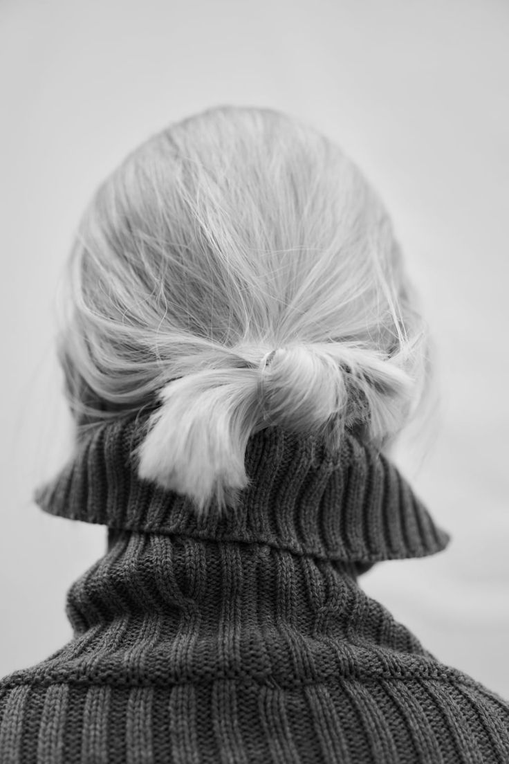 the back of a woman's head wearing a sweater with a white fur pom - pom