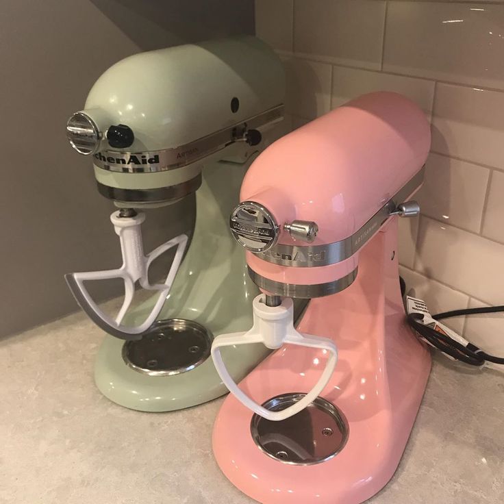 two pastel colored mixers sitting on top of a counter next to each other