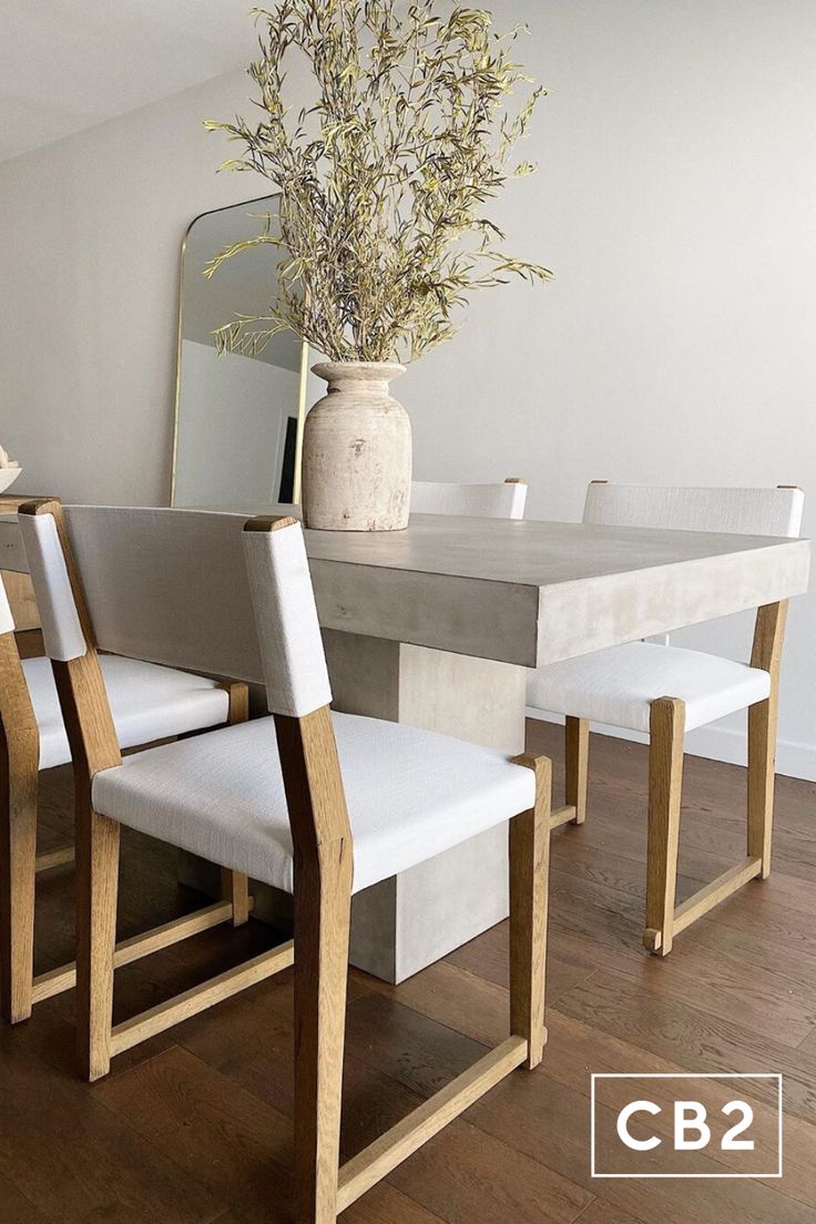 a dining room table with four chairs and a vase filled with flowers on top of it