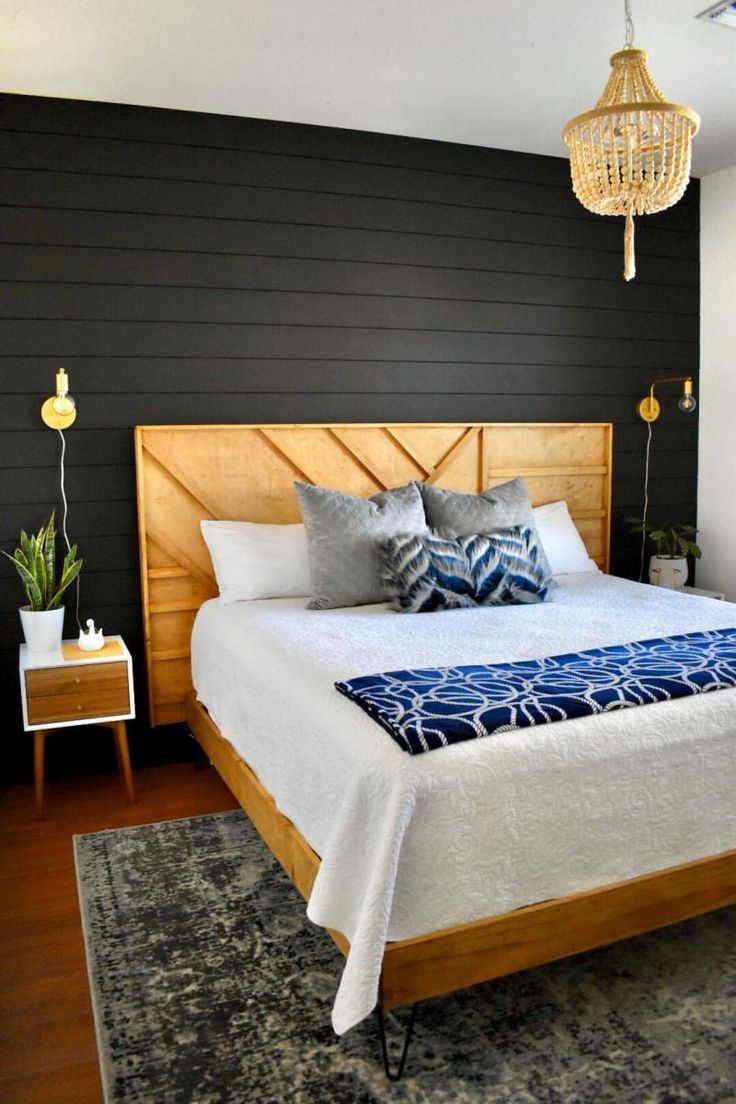 a bedroom with black walls and white bedding, wooden headboard and foot board