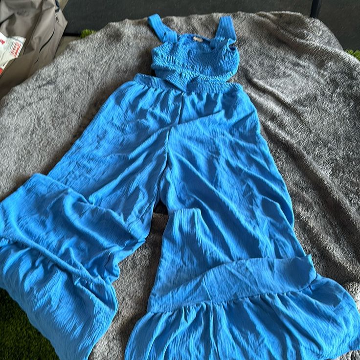 Stretchy Ruched Top With Cut Out Sides And Back With Wide Led Tiered Bottoms. Never Worn Blue Overalls For Beach In Spring, Blue Wide-leg Jumpsuits And Rompers For Day Out, Chic Blue Wide-leg Jumpsuits And Rompers, Chic Blue Wide Leg Jumpsuits And Rompers, Wide Leg Blue Jumpsuit For Day Out, Sleeveless Summer Jumpsuits And Rompers Matching Set, Sleeveless Matching Set Jumpsuits And Rompers For Summer, Blue Two-piece Set For Day Out, Blue Pants From Matching Set