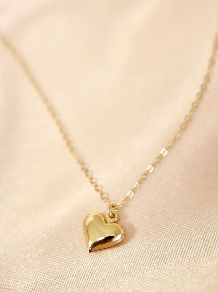 This necklace features a brass-plated puff heart charm on an 18" gold-filled chain. Crafted from premium materials including gold-filled chain and a brass heart charm, this necklace is sure to make a statement. Length: 18" long Everyday Brass Heart Pendant Jewelry, Dainty Heart-shaped Brass Jewelry, Gold-tone Heart Necklace With Adjustable Chain, Gold-tone Heart Pendant Necklace With Adjustable Chain, Heart-shaped Brass Necklace With Adjustable Chain, Everyday Gold Heart Necklace With Adjustable Chain, Heart Shaped Brass Necklaces, Yellow Gold Heart-shaped Brass Necklace, Heart Shaped Yellow Gold Brass Necklace