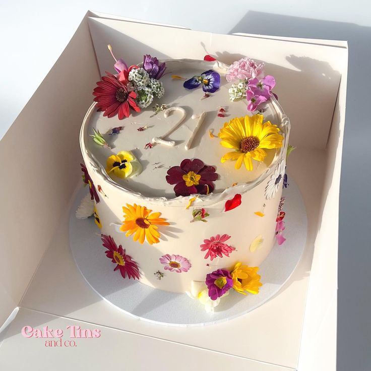 a white cake with flowers on it in a box