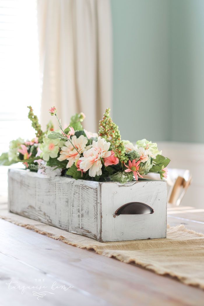 a wooden box filled with flowers sitting on top of a table next to a window